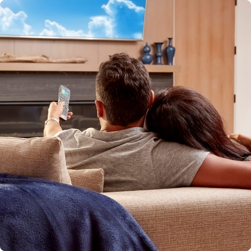 Couple on a couch using URC Total Control Lite to control their home
