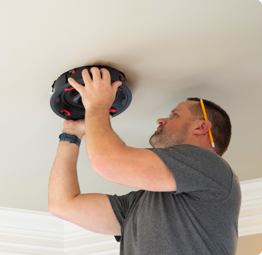 Man installing an Episode subwoofer in the ceiling