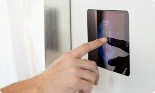 Hand pressing touchpad mounted in wall