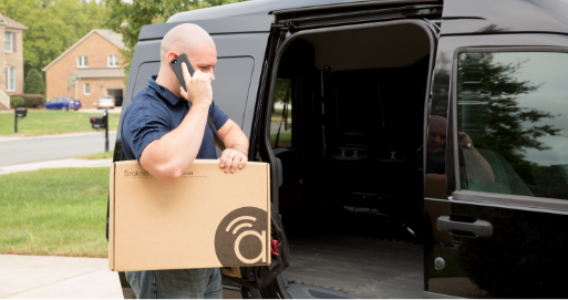 Dealer talking on phone holding Araknis box