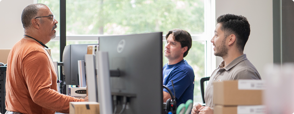 Men standing around computers