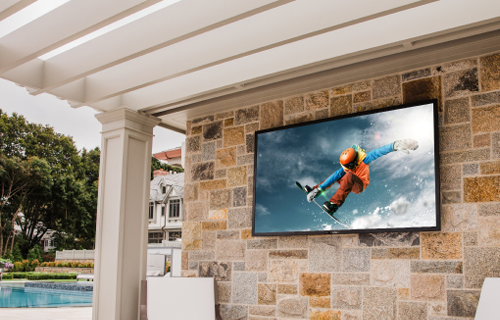 Sunbrite television installed in wall beside a pool