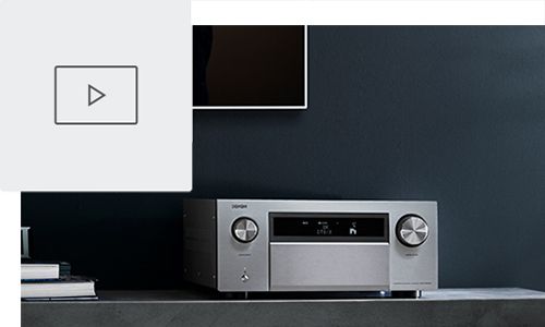 AVR on entertainment stand below TV with play button icon in top left corner