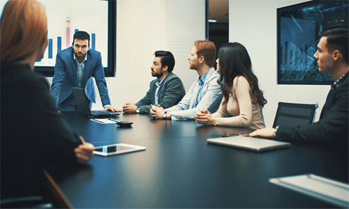 Image of group of people sitting at a table in a board room  />
		</div>
		<div class=