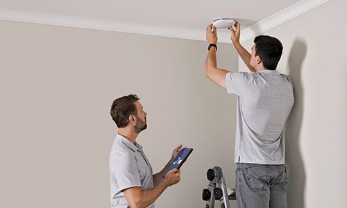 Two people installing access point on ceiling