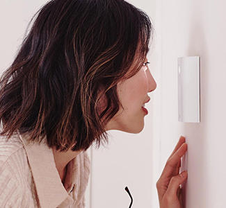 Woman looking through a peephole on door