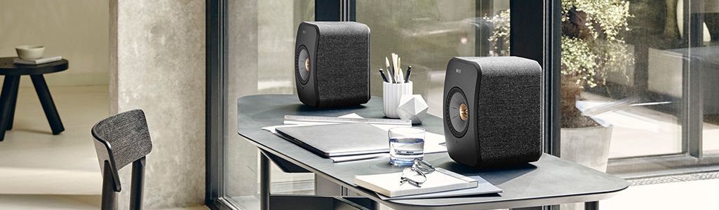 Black KEF speakers on a work desk