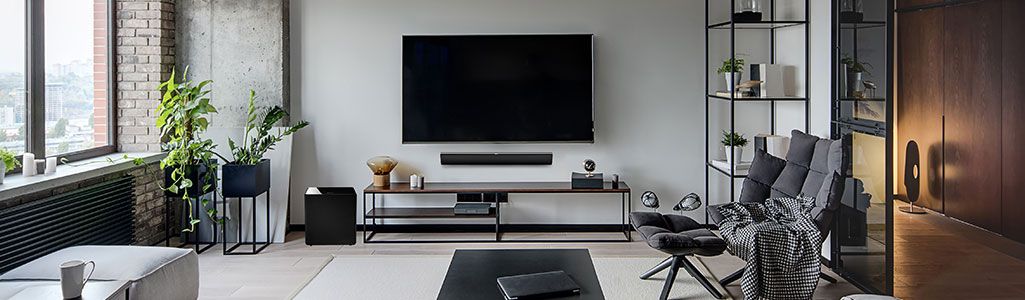 Soundbar mounted below a flat screen TV in a contemporary living room