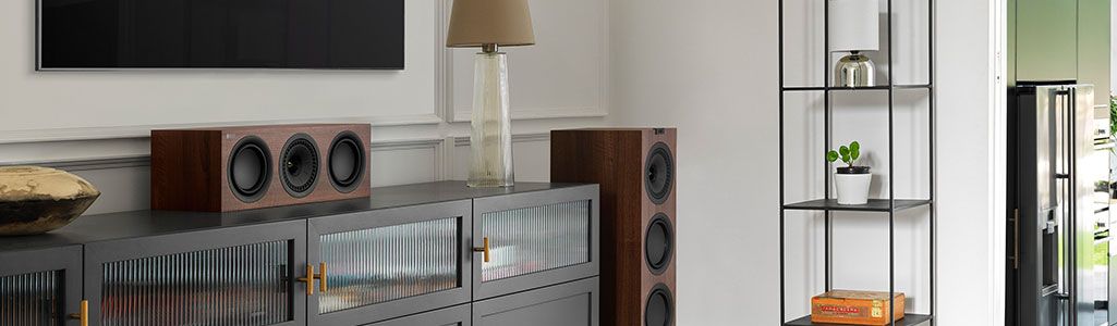 Walnut KEF Q250C Speakers placed on and beside a cabinet