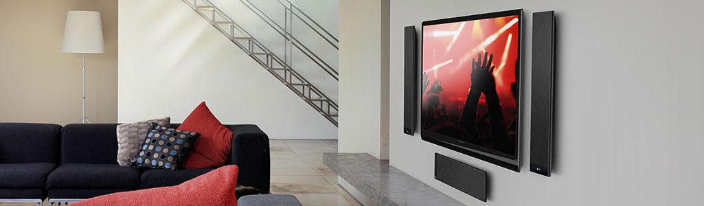KEF T series speakers hanging on wall around a flat screen TV in Room