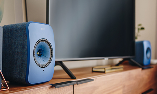 KEF LSX speakers on top of cabinet with flat screen TV