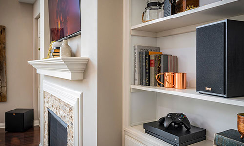 Angled view of bookshelf speaker with a black grilles on shelf in living room