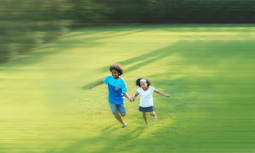 2 kids running in a field