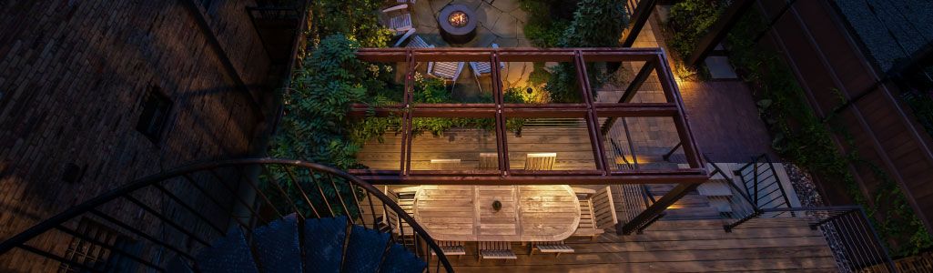 View looking down on seating area on deck of house that is lit up