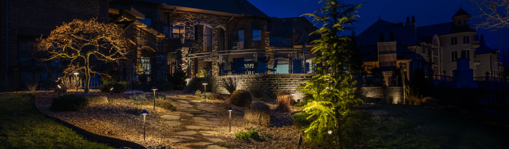 Outdoor backyard hardscape scene of large stone house with lights